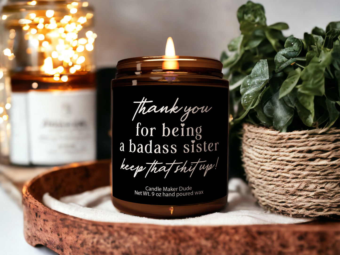 a candle sitting on top of a wooden tray next to a potted plant