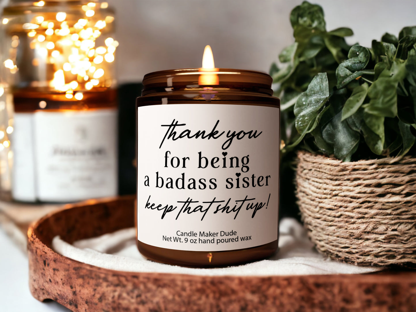 a candle sitting on top of a wooden tray next to a potted plant